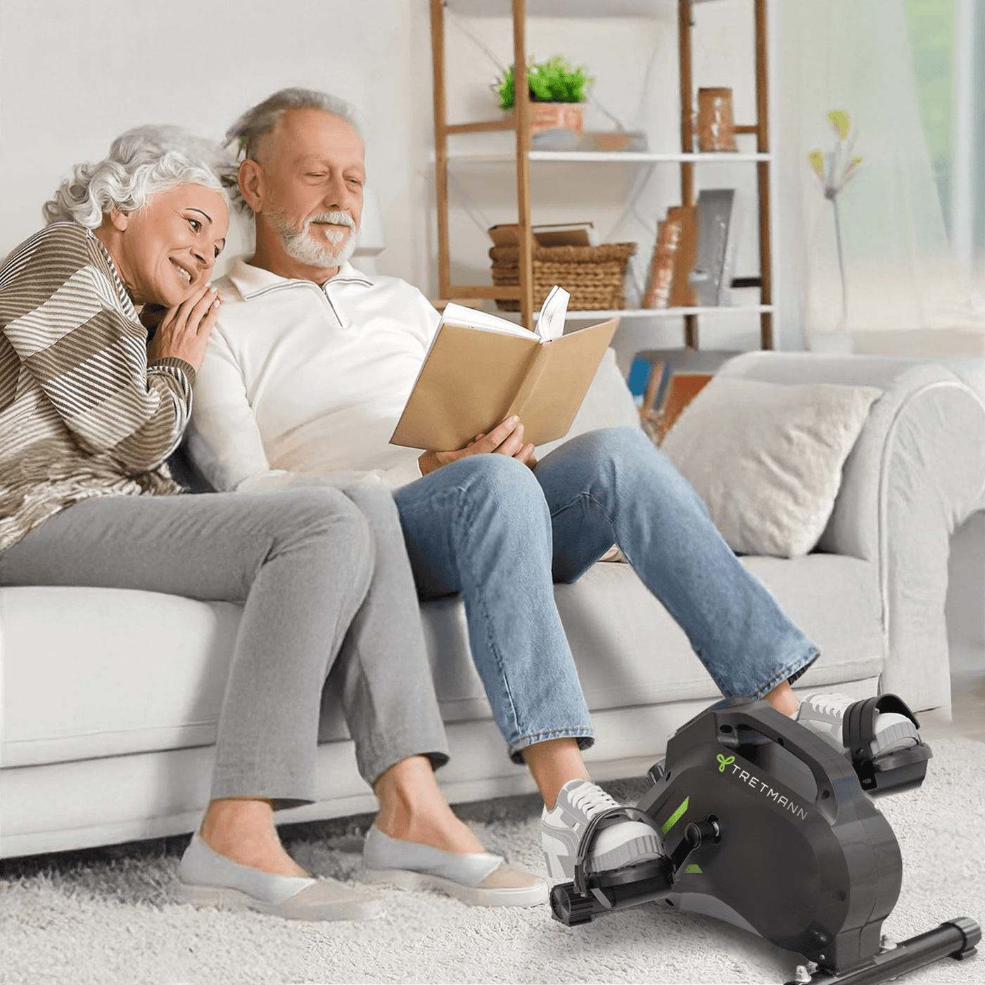 Zwei Senioren nutzen einen mini Heimtrainer für Senioren, während sie auf der Couch sitzen